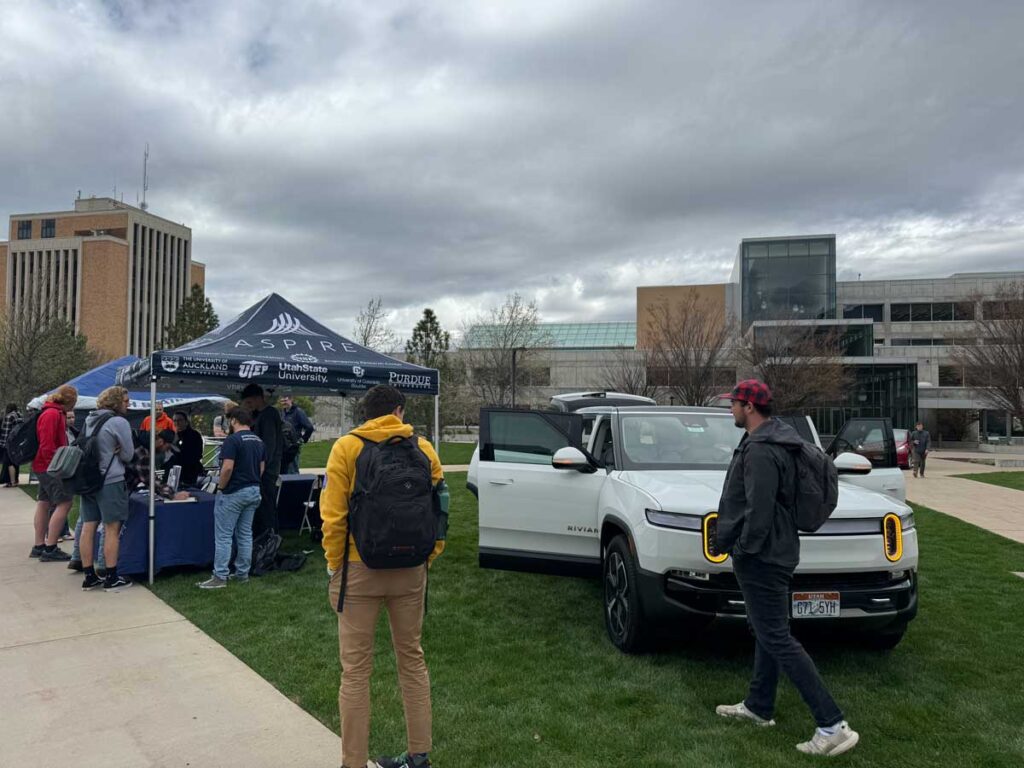Students admire a Rivian R1S and other electric vehicles while learning about the ASPIRE Research Center during a tech showcase on USU's engineering quad.