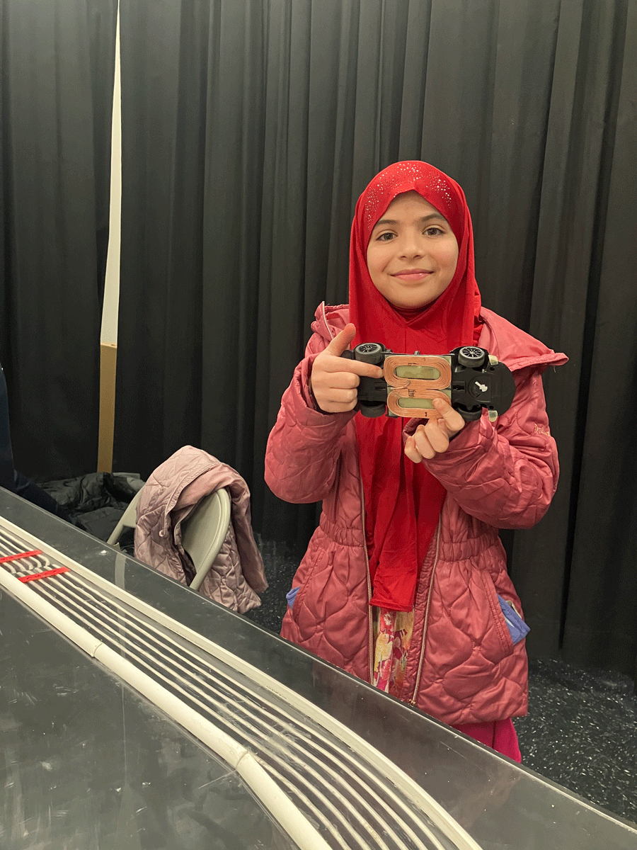 Abdulla Baig's daughter holding up a model car at the STEM fair.