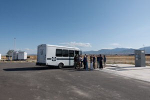 ASPIRE students gather outside of the ASPIRE mini bus in front of the 1 MW DWPT charger at the Utah Inland Port.