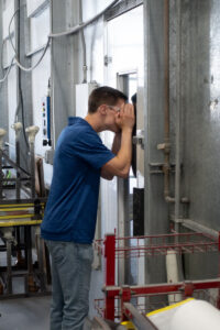 ASPIRE student peering into the painting room at Kenworth Sales Co.