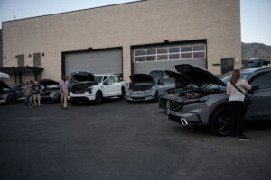 Several electric vehicles with their hoods up for viewing at the EVR Open House.