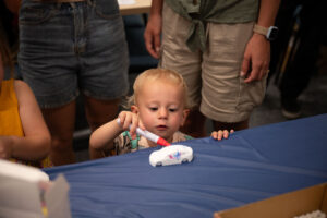 A young child colors her 3D printed car.