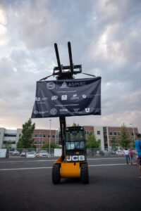A fully electric forklift displays a banner of all of the core ASPIRE campuses.