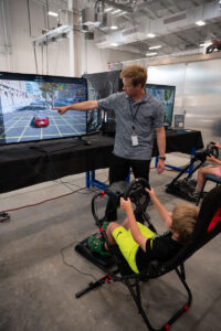 ASPIRE student explains to young drivers how the EV driving simulation works.