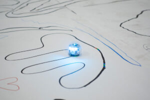 A glowing ozobot follows the path a guest drew.
