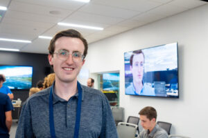 ASPIRE student poses in front of his video highlight playing on the TV.