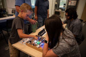 Child explores ASPIRE student's demonstration of a Smart Grid Model.
