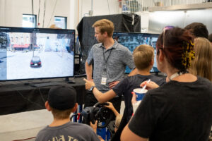 Guest and ASPIRE student watch EV driving simulation.