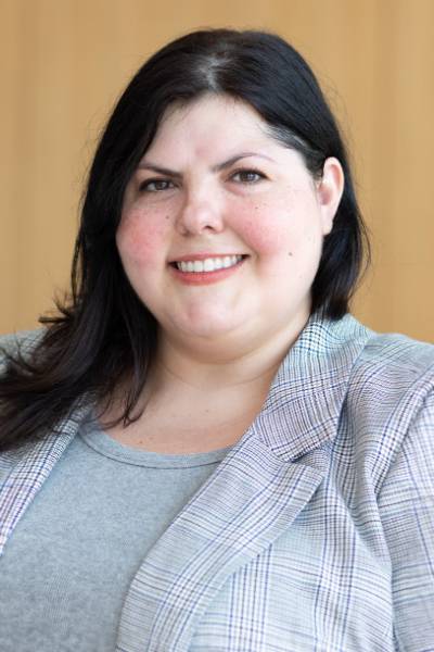 Sarah Grajdura smiling in front of a brown background.