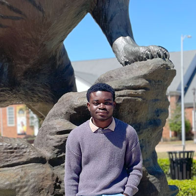 Aaron Paddy poses in front of a statue.