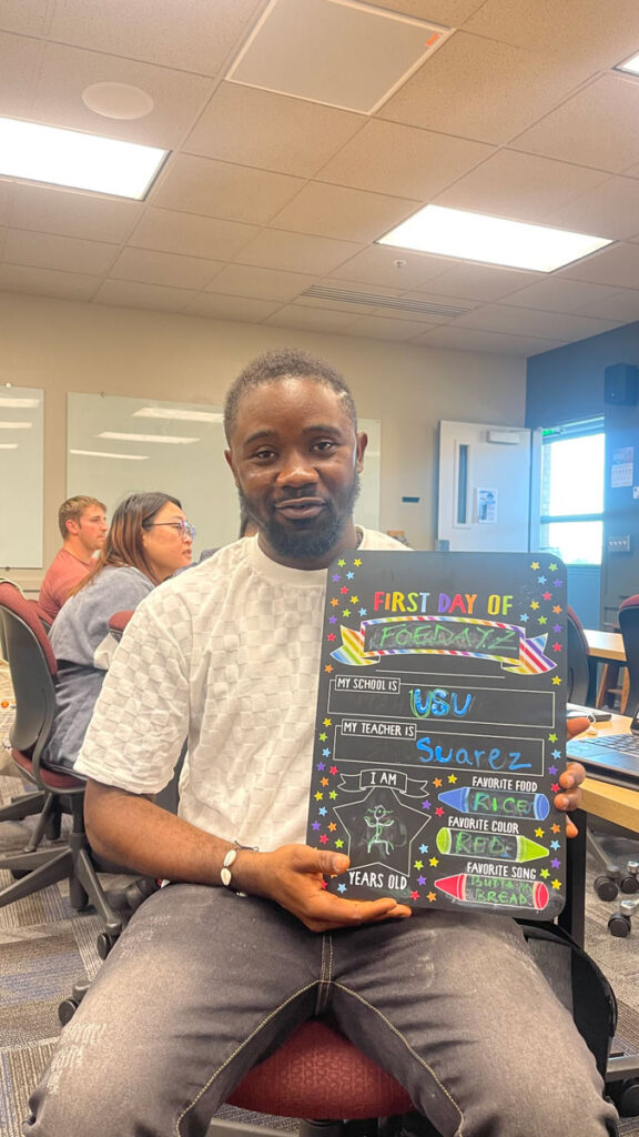 Foeday holding an colorful chalkboard with his name and a few things about him.