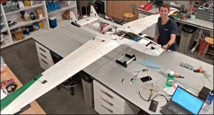 Jon Silberstein, one of the lead authors of the paper, working on the project. The wings of a model plane can be seen extending on either side of a work table.
