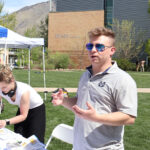 Mackay Baugh at a table explaining his research during USU's Research Week.