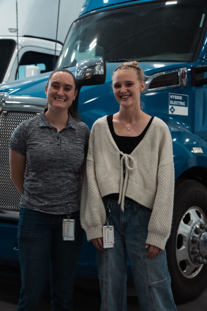 Hope Miller and Whitney Walpole in front of the Hybrid Electric blue semi truck.